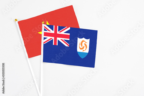 Anguilla and Vietnam stick flags on white background. High quality fabric, miniature national flag. Peaceful global concept.White floor for copy space.