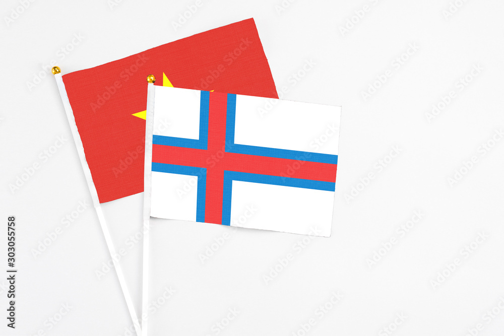 Faroe Islands and Vietnam stick flags on white background. High quality fabric, miniature national flag. Peaceful global concept.White floor for copy space.