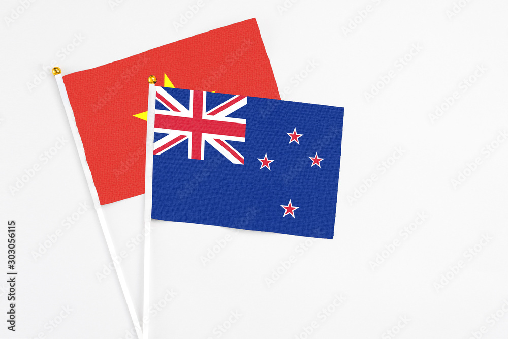 Fototapeta premium New Zealand and Vietnam stick flags on white background. High quality fabric, miniature national flag. Peaceful global concept.White floor for copy space.