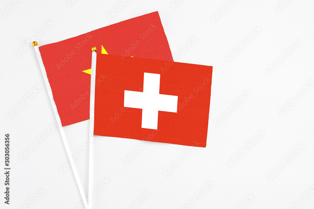 Switzerland and Vietnam stick flags on white background. High quality fabric, miniature national flag. Peaceful global concept.White floor for copy space.