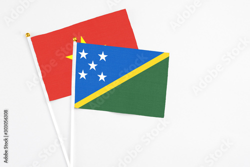 Free Download Solomon Islands and Vietnam stick flags on white background. High quality fabric, miniature national flag. Peaceful global concept.White floor for copy space. - GFXLoad