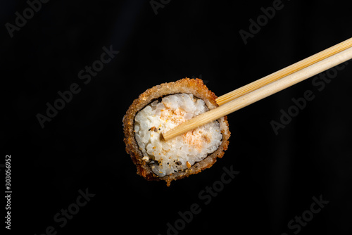 Breaded Sushi - Hot Roll. Woman picking sushi with chopstick. Black background.