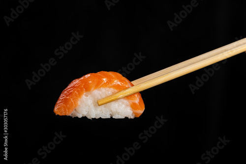 Nigiri Sushi. Woman picking sushi with chopstick. Black background.