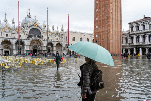 VENICE, ITALY - November 12, 2019: St. Marks Square (Piazza San Marco) during flood (acqua alta) in Venice, Italy. Venice high water. Tourists at St. Mark's Square during high water