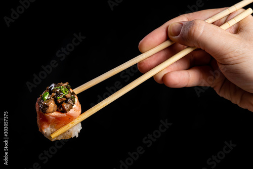 Funghi Sushi. Woman picking sushi with chopstick. Black background.