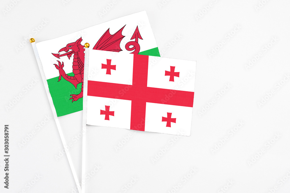 Georgia and Wales stick flags on white background. High quality fabric, miniature national flag. Peaceful global concept.White floor for copy space.