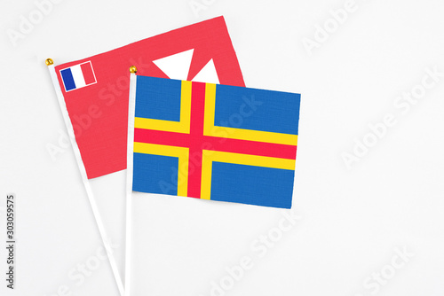 Aland Islands and Wallis And Futuna stick flags on white background. High quality fabric, miniature national flag. Peaceful global concept.White floor for copy space. photo