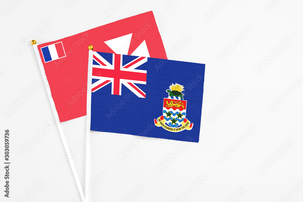 Fototapeta premium Cayman Islands and Wallis And Futuna stick flags on white background. High quality fabric, miniature national flag. Peaceful global concept.White floor for copy space.