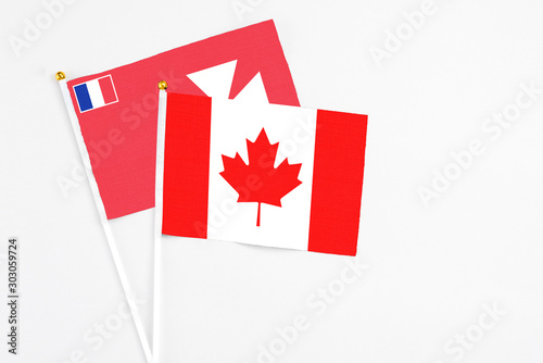 Canada and Wallis And Futuna stick flags on white background. High quality fabric, miniature national flag. Peaceful global concept.White floor for copy space.