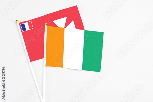 Cote D'Ivoire and Wallis And Futuna stick flags on white background. High quality fabric, miniature national flag. Peaceful global concept.White floor for copy space.