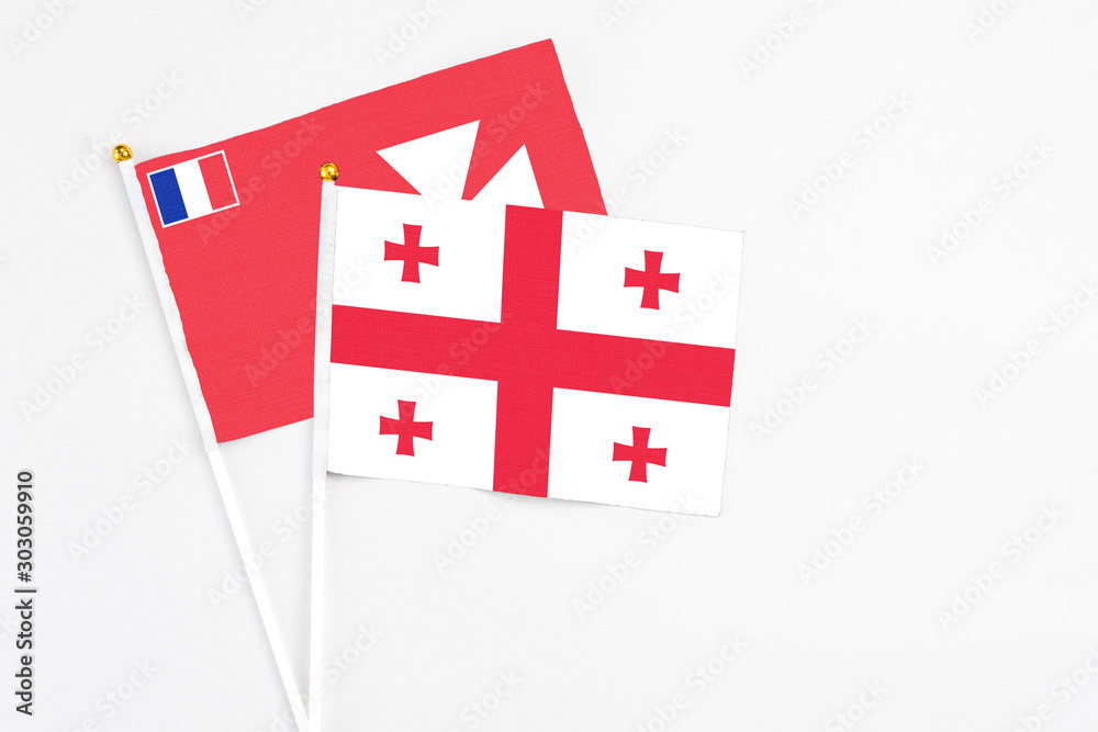 Georgia and Wallis And Futuna stick flags on white background. High quality fabric, miniature national flag. Peaceful global concept.White floor for copy space.