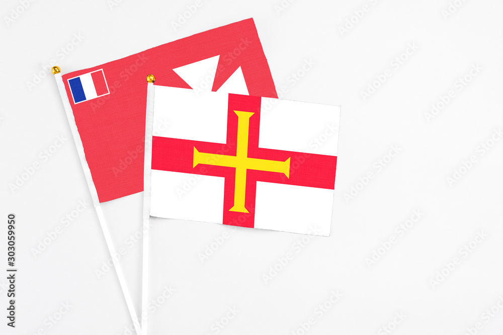 Guernsey and Wallis And Futuna stick flags on white background. High quality fabric, miniature national flag. Peaceful global concept.White floor for copy space.