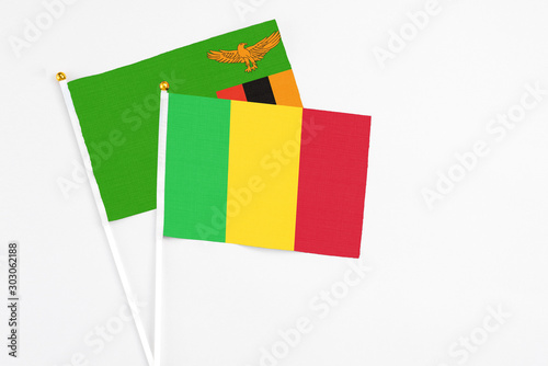 Mali and Zambia stick flags on white background. High quality fabric, miniature national flag. Peaceful global concept.White floor for copy space.