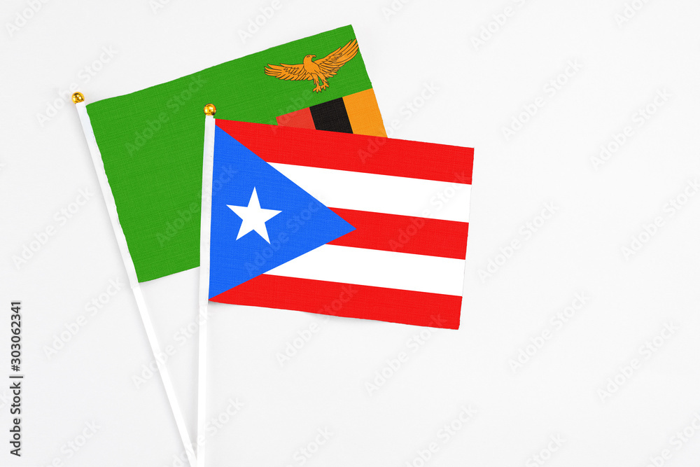 Puerto Rico and Zambia stick flags on white background. High quality fabric, miniature national flag. Peaceful global concept.White floor for copy space.