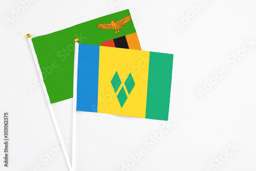 Saint Vincent And The Grenadines and Zambia stick flags on white background. High quality fabric, miniature national flag. Peaceful global concept.White floor for copy space.