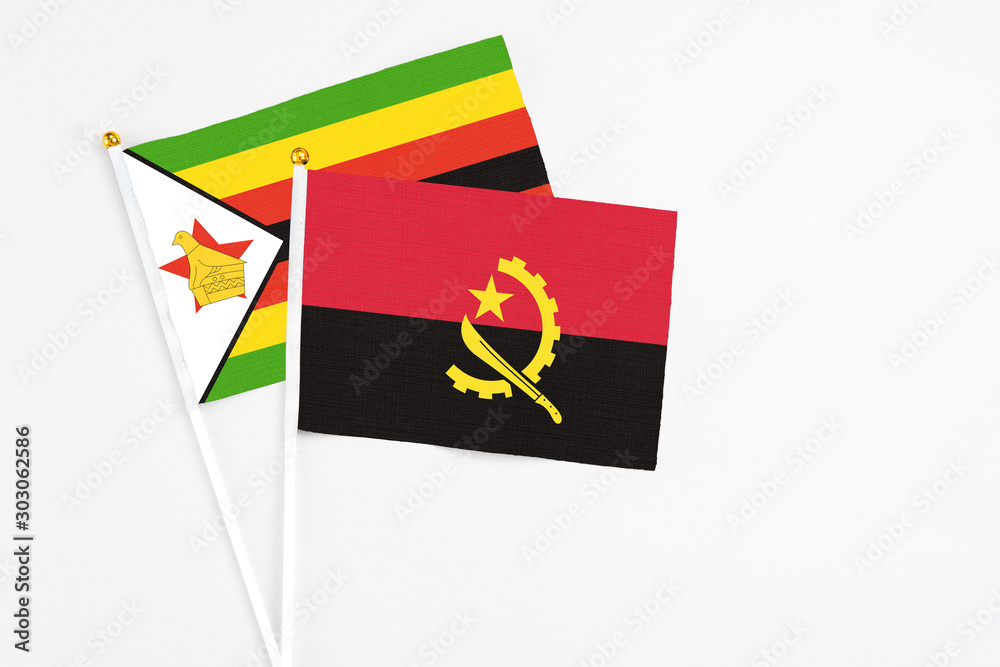 Angola and Zimbabwe stick flags on white background. High quality fabric, miniature national flag. Peaceful global concept.White floor for copy space.