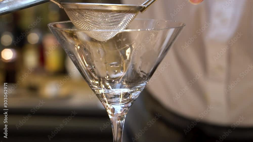 close up shot of a bartender pouring a mix cocktail of a coffee based alcohol drink in slow motion during the Chicago star bucks grand opening. the liquid pours smoothly into the martini glass