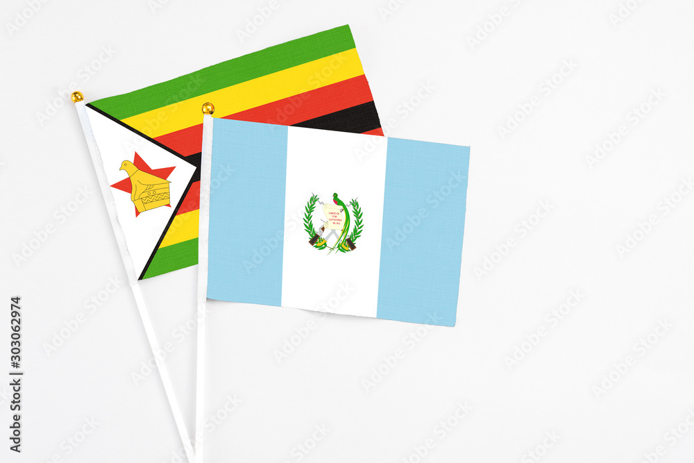Guatemala and Zimbabwe stick flags on white background. High quality fabric, miniature national flag. Peaceful global concept.White floor for copy space.