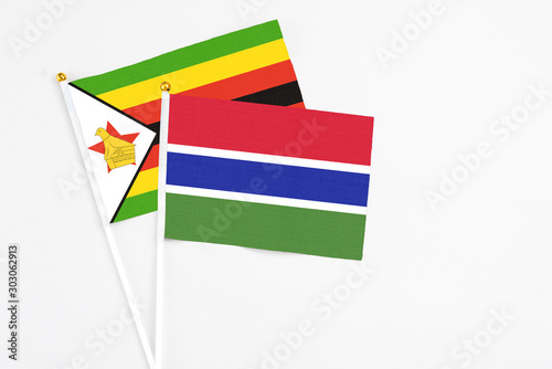 Gambia and Zimbabwe stick flags on white background. High quality fabric  miniature national flag. Peaceful global concept.White floor for copy space.