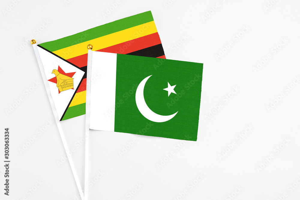 Pakistan and Zimbabwe stick flags on white background. High quality fabric, miniature national flag. Peaceful global concept.White floor for copy space.