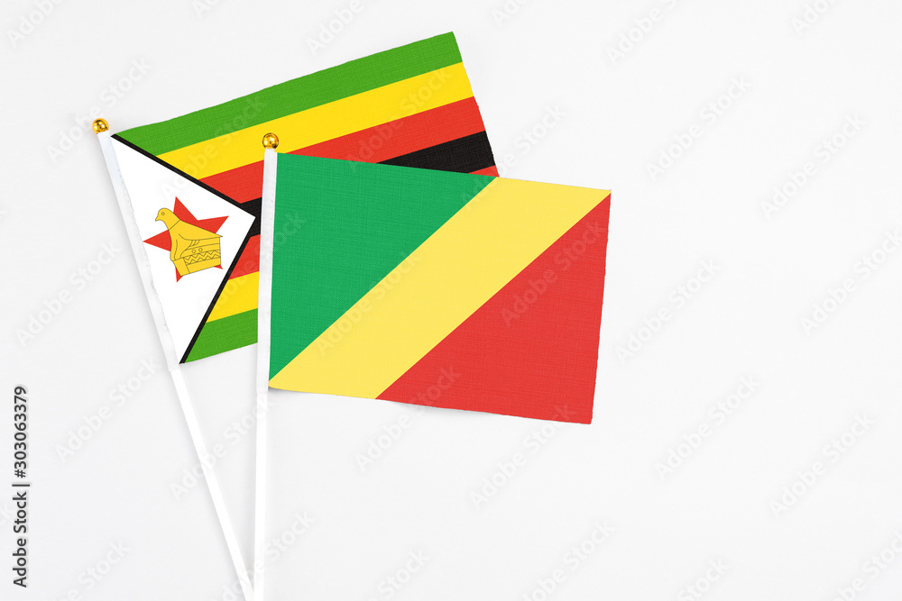 Republic Of The Congo and Zimbabwe stick flags on white background. High quality fabric, miniature national flag. Peaceful global concept.White floor for copy space.