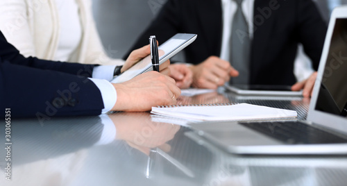 Business people discussing contract working together at meeting at the glass desk in modern office. Unknown businessman and woman with colleagues or lawyers at negotiation. Teamwork and partnership