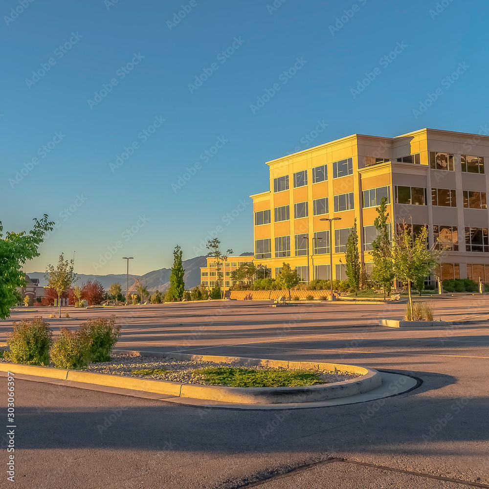 Square Facade of a contemporary office building with parking lot on a sunny day