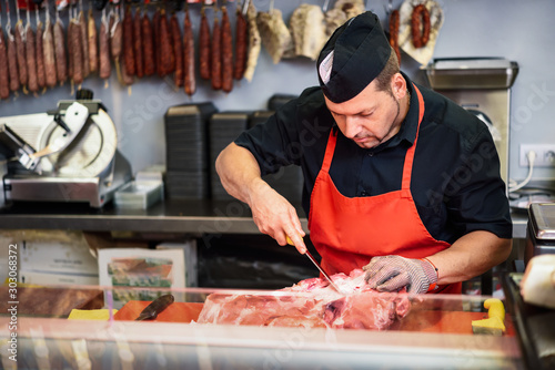 Butcher boning fresh ham in a modern butcher shop photo