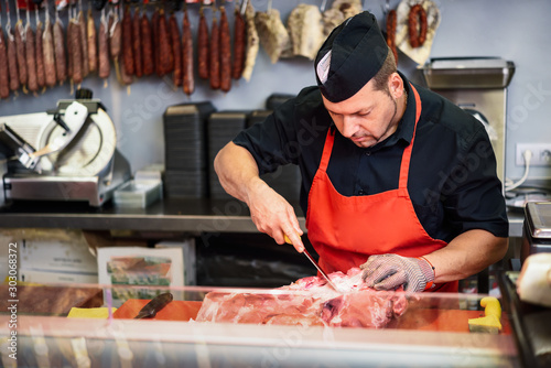 Butcher boning fresh ham in a modern butcher shop