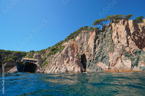 Rocky coastal cliff with a boat seen from sea surface, Spain, Mediterranean, Costa Brava, Catalonia, Aigua Xelida, Palafrugell photo