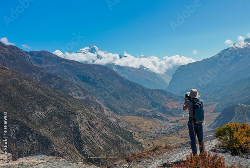  Asian man trekker in valley of Everest base camp trekking route in Khumbu ,Nepal with snow mountain in background.