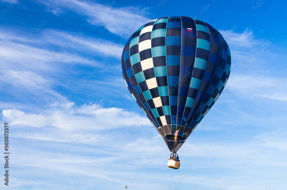 Fototapeta premium Hot air balloon with a burning burner scorched the envelope against the blue sky.