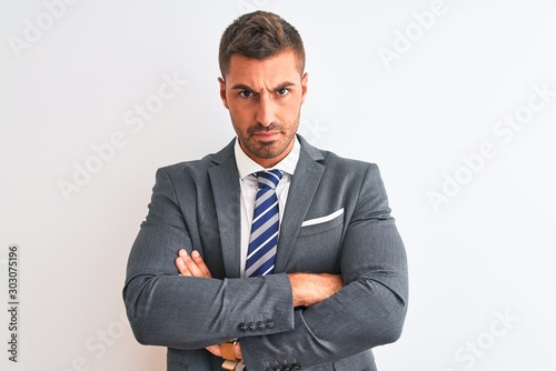 Young handsome business man wearing suit and tie over isolated background skeptic and nervous, disapproving expression on face with crossed arms. Negative person.