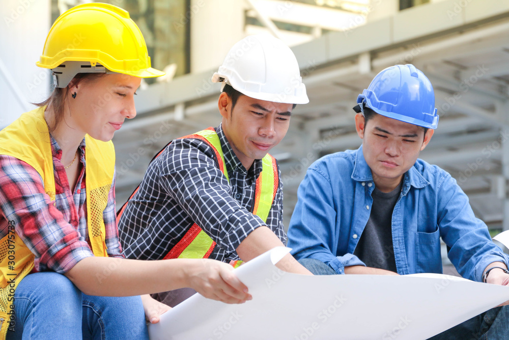 Fototapeta premium Engineer team meeting and looking on drawing paper or plan with project building construction in city background
