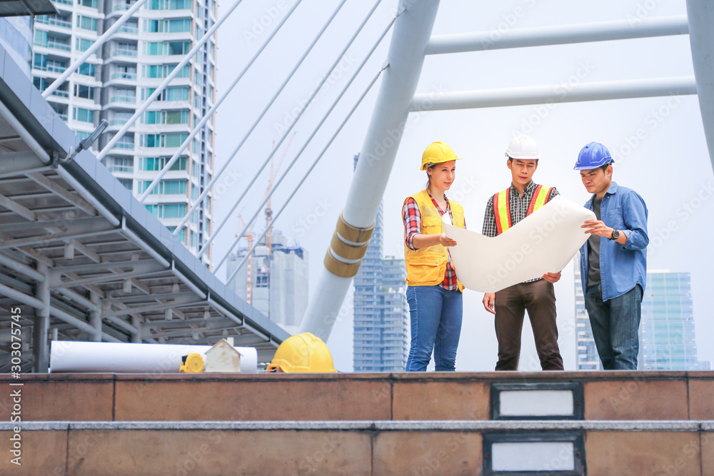 Engineer team meeting and looking on drawing paper or plan with project building construction in city background Engineer team meeting and looking on drawing paper or plan with project building construction in city background