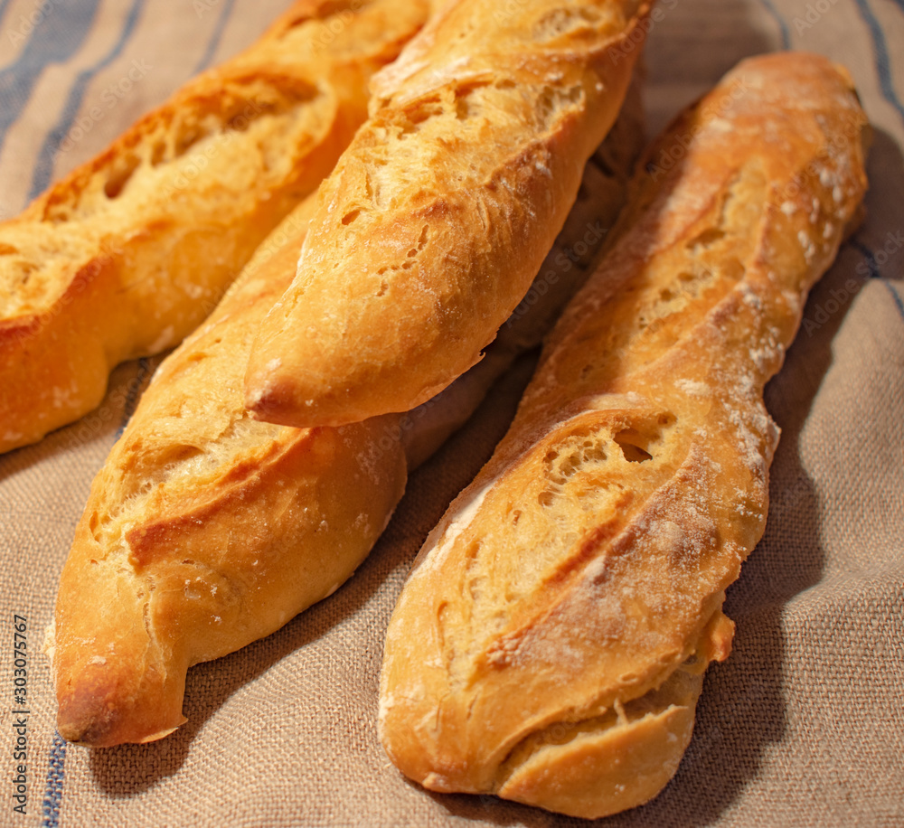French baguettes on linen towel in morning sunshine. Food background