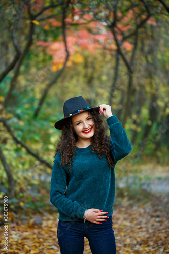 girl in the autumn forest with a hat in her hands