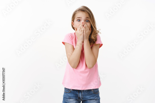 Scared troubled young cute blond little girl calling for help, panicking, feel frightened gasping shocked cover mouth with palms, scared camera upset and speechless, worry for friend got in trouble