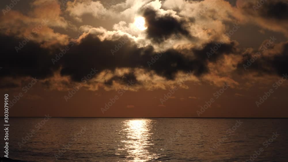 The shine shines and reflects in the ocean water as dramatic storm clouds hang overhead in this magical beach and ocean seascape scene that seems as surreal as it does ethereal and artistic. The shine shines and reflects in the ocean water as dramatic storm clouds hang overhead in this magical beach and ocean seascape scene that seems as surreal as it does ethereal and artistic.