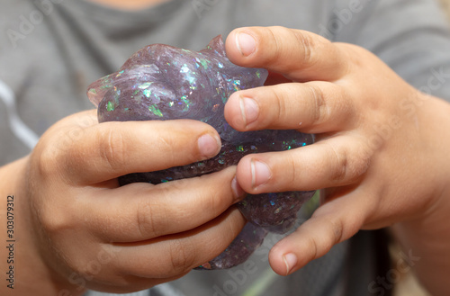 A boy plays with a slime in his hands