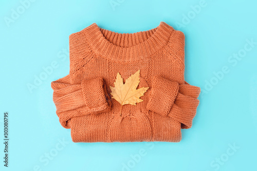 Yellow autumn leaf on orange knitted sweater background, top view flat lay.