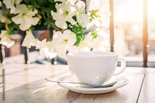 White big cup of delicious coffee on wooden table in sunset light with copy space.