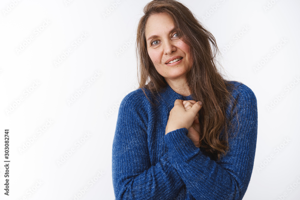 Charming middle-aged mother in blue sweater pressing hands to chest in touched and lovely pose tilting gazing at camera as delighted watching how kids grew up, posing dreamy and accomplished Charming middle-aged mother in blue sweater pressing hands to chest in touched and lovely pose tilting gazing at camera as delighted watching how kids grew up, posing dreamy and accomplished