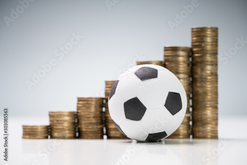 Soccer Ball In Front Of Coin Stacks On White Desk