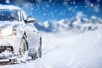 Luxury car on winter road, blur mountains background. Tires on snow highway.