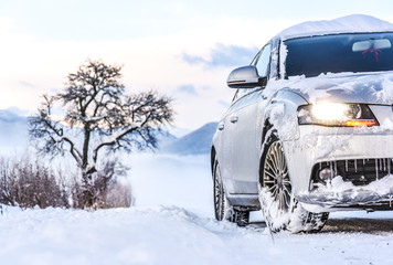 Luxury car in winter on snowy road. Tires on snow.
