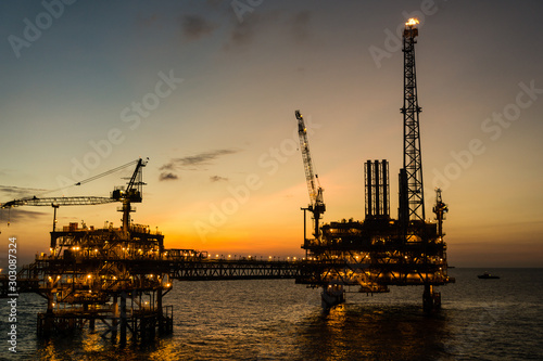 Tableau sur toile Silhouette of oil production platform during sunset