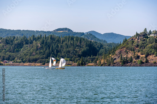 Sailing along the Columbia River with forests on the hills and mountains in the Hood River on a sunny day