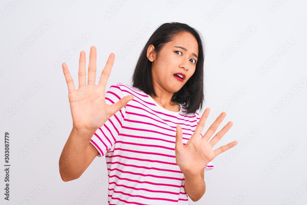 Young chinese woman wearing striped t-shirt standing over isolated white background afraid and terrified with fear expression stop gesture with hands, shouting in shock. Panic concept. Young chinese woman wearing striped t-shirt standing over isolated white background afraid and terrified with fear expression stop gesture with hands, shouting in shock. Panic concept.