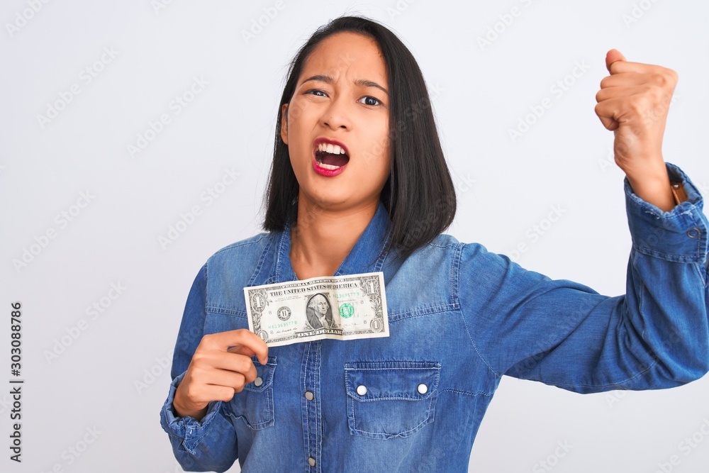 Young beautiful chinese woman holding one dollar standing over isolated white background annoyed and frustrated shouting with anger, crazy and yelling with raised hand, anger concept Young beautiful chinese woman holding one dollar standing over isolated white background annoyed and frustrated shouting with anger, crazy and yelling with raised hand, anger concept